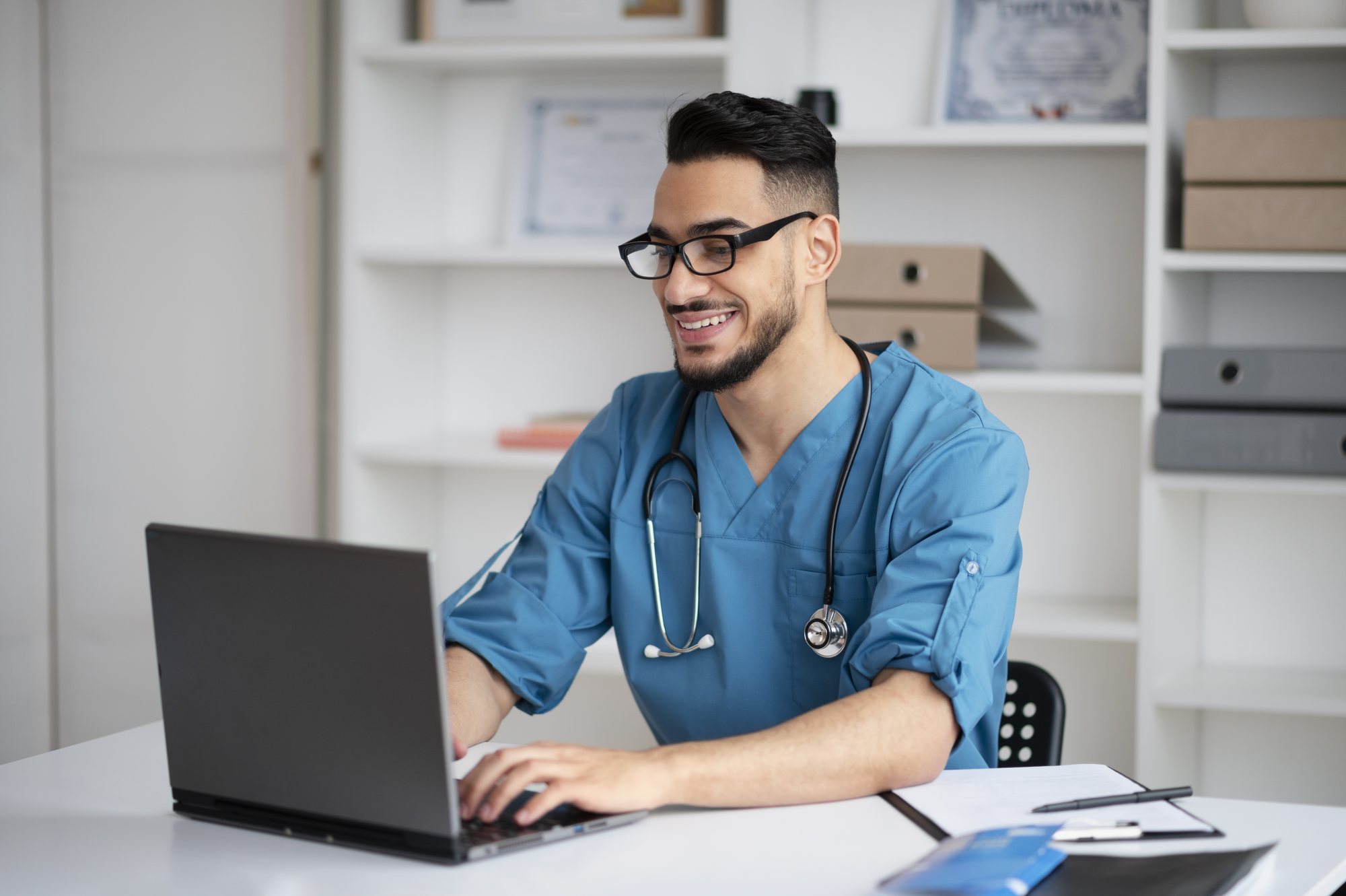 Enfermeiro sorrindo enquanto usa o notebook no consultório